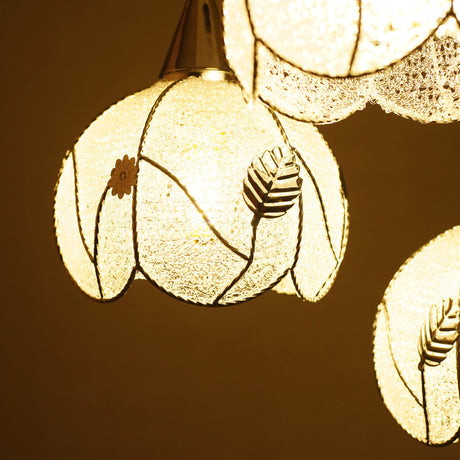 A detailed close-up of the illuminated floral glass pendant lights, highlighting their textured glass and floral engravings.
