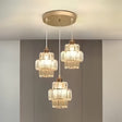 A three-light pendant chandelier with gold and glass accents, suspended from a gold ceiling mount.