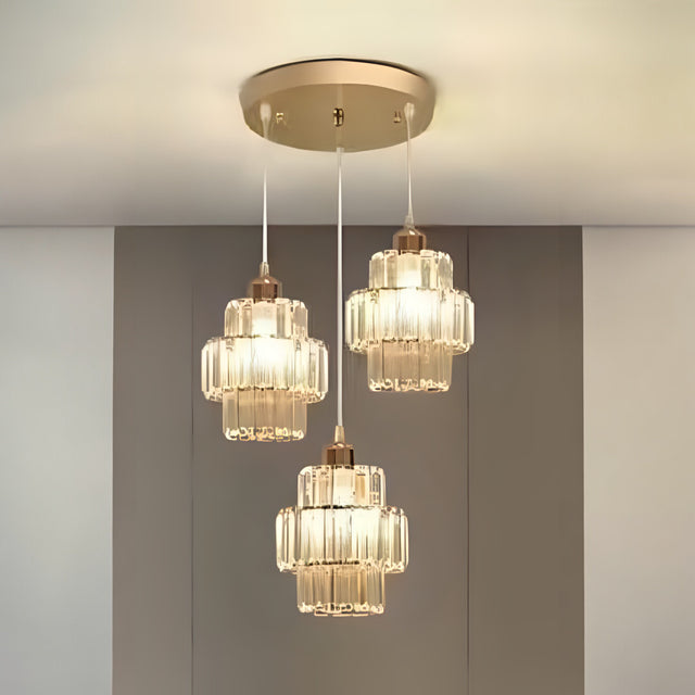 A three-light pendant chandelier with gold and glass accents, suspended from a gold ceiling mount.