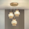 A three-light pendant chandelier with gold and glass accents, suspended from a gold ceiling mount.