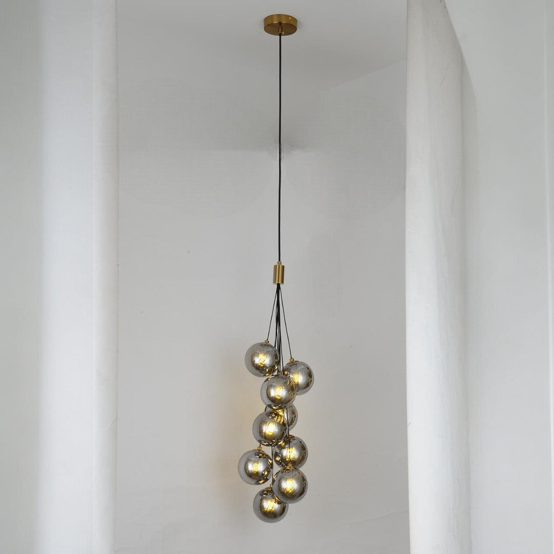 A cascading pendant light with multiple grey glass spheres suspended at varying heights, creating an elegant and artistic look.