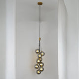 A cascading pendant light with multiple grey glass spheres suspended at varying heights, creating an elegant and artistic look.