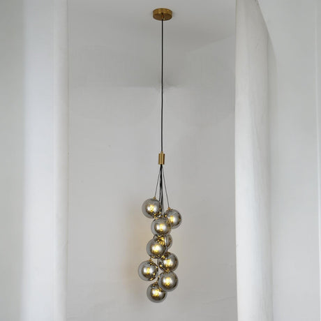 A cascading pendant light with multiple grey glass spheres suspended at varying heights, creating an elegant and artistic look.