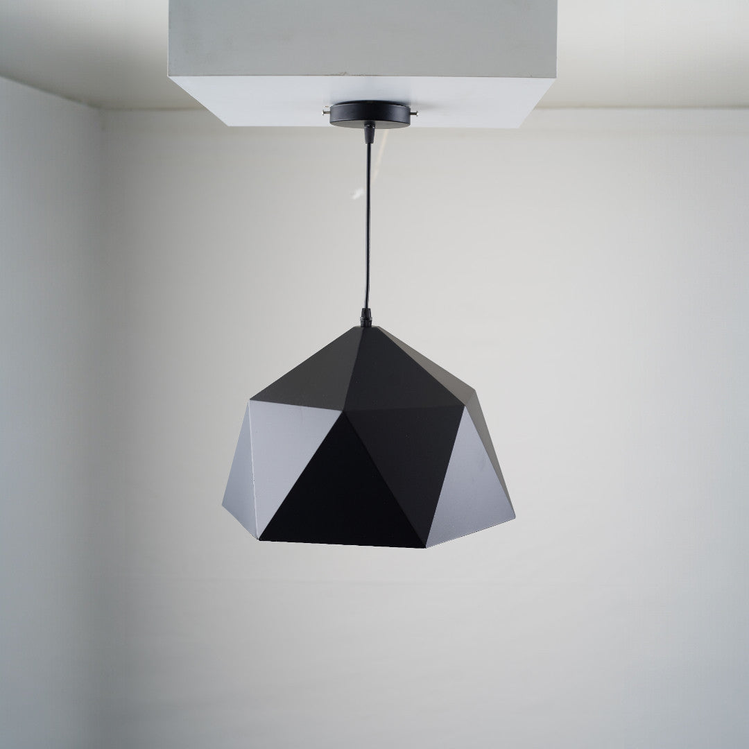 A geometric black pendant light with a faceted, polygonal design is suspended from a white ceiling. The fixture is fixed directly to a square ceiling mount.
