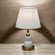 Classic white and gold table lamp with a bottle-shaped metal base and a white fabric shade.
