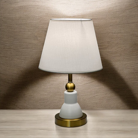 Classic white and gold table lamp with a bottle-shaped metal base and a white fabric shade.
