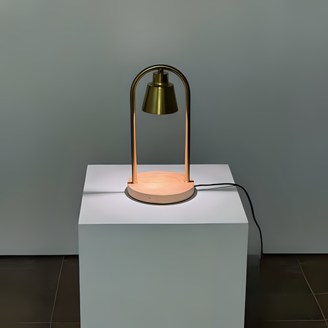 A sleek table lamp featuring a metallic arched handle and a cylindrical light, positioned on a white pedestal.
