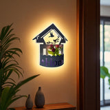 Wall-mounted LED light fixture designed in the shape of a white house , featuring a cork-style built-in compartment holding artificial pink and red tulip flowers. The light has a whimsical, cottage-inspired aesthetic and is mounted on a plain white wall.