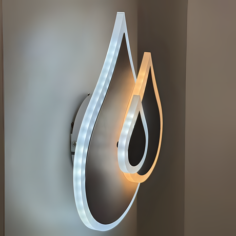 Wall-mounted LED light fixture shaped like two overlapping water droplets, with a soft white and warm white glow illuminating the surrounding wall.