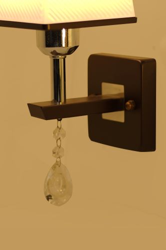 A contemporary brown wall sconce with a square base and a small dangling crystal, featuring a sleek modern design.