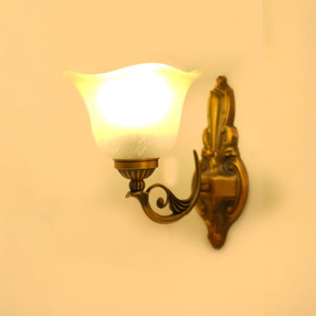 A vintage-style metal wall lamp with a frosted glass shade, equipped with a led lamp E27 illuminating a warm yellow light against a beige wall.