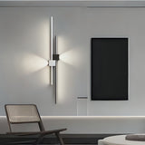A minimalist vertical wall light with two slim LED strips forming a cross pattern, installed in a modern living room.